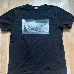 The Ripper t-shirt - Ett egendegnat tryck på en fräsch secondhandtröja. Ett tryck från vår kollektion ”Noire et Blanche”. Vårt motiv ’The Ripper’ är en målning inspererad av ett foto, taget 1900 på Mabel Arch Underground Station, London.