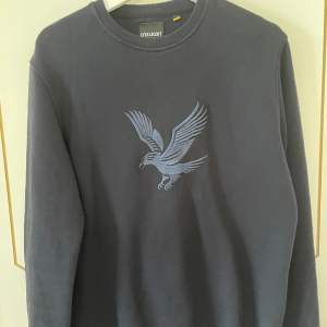 Lyle & Scott sweatshirt i nyskick. Den är marinblå med tryck på bröstet. Storlek S. Köparen står för frakten.