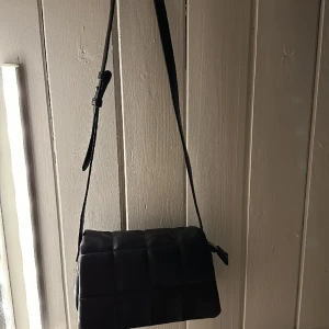 Axelremsväska  - Axelremsväska svart. Med ”rutigt” mönster 