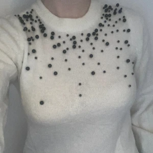 Stickad tröja H&M - Vit stickad tröja med svarta pärlor i olika storlekar från H&M. Strl XS men passar bra på S/M-kropp också. Varsamt använd någon gång bara.   Köparen står för frakt. Diskuterbart pris. Hör av er för fler bilder eller frågor. 
