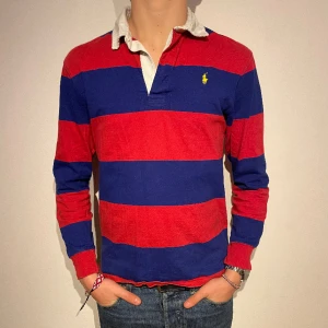 Ralph-Lauren tröja  - Charmig polo tröja i blått och rött. Tröjan är inte ny med fullt fungerande.