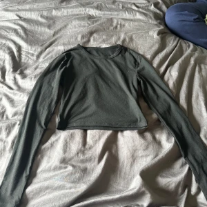 Svart croppad långärmad tröja - En svart croppad långärmad tröja i ett mjukt och bekvämt material. Tröjan har en enkel design med rund halsringning och är perfekt för vardagsbruk.