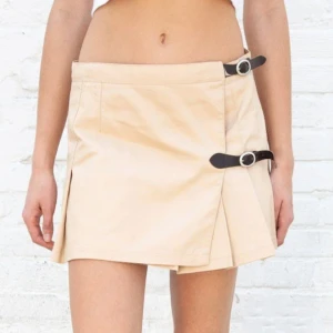 Brandy Melville kjol - Jättefint kort brandy kjol, beige färg med svart läder spänne. Aldrig Andvänd, dock saknar denna kjolen det nedre läderbältet eftersom jag sprättade bort det för bättre passform. Men den är fortfarande lika fin. Storlek one size, passar xs-s