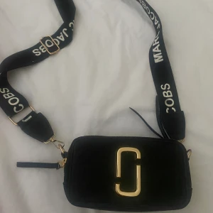 Marc Jacobs Väska - Säljer denna helt oanvända Marc Jacobs väskan som är helt svart med gulddetaljer. 