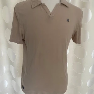 beige pike Morris - den är 98 cm runt bröstet och längden på t-shirten är 67 cm från topp till botten den är i bra skick aldrig andvänt den är 55 % bomull och 45% linne