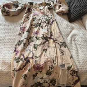 Blommig klänning  - Säljer denna blommiga klänningen från H&M som är helt oanvänd (etikett kvar). Den har liten slits och öppen rygg med knytning💐🌸🌸