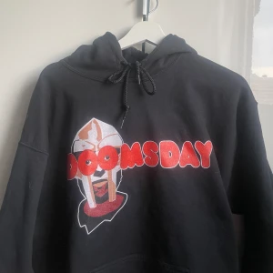 MF DOOM ”DOOMSDAY” Hoodie - Riktigt fet MF DOOM hoodie som ej användts pga för liten, storlek L men passar M perfekt. Riktigt bra skick då den inte kommit till användning alls, helt lungt o skriva om du har fler frågor eller något. 