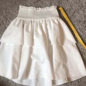 Vit volangkjol  - Vit volangkjol i bra skick. Perfekt nu inför sommaren. Storleken är 12-13y/Xs. Den är knappt använd och i bra skick. 