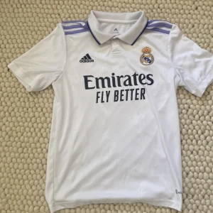 Äkta Real Madrid hemmaställ säsongen 21/22  - Jag säljer min gamla real Madrid tröja som jag köpte i Paris under Champions League finalen 2022 den är köpt i officiella Champions League butiken  Skick 10/10 är bara använd en gång under Champions League finalen  Pris kan diskuteras 
