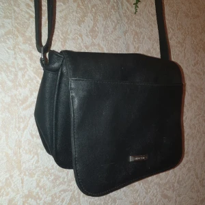 Handväska  - Svart handväska med många fickor. Mycket plats för förvaring. Använd flera gånger, lite sliten men fortfarande i bra skick. Justerbar. Mått: 22×17cm