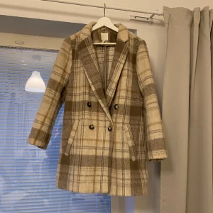 Kappa - Beige, rutig kappa från Hm. Storlek 40, sitter lagom oversize på mig som annars har  xs. 15% ull. Snygg och passar till mycket. Nypris 399kr💗
