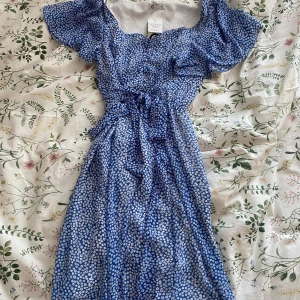 Blommig klänning - Jättesöt klänning med snörning i midjan från Cubus köpt förra året, aldrig använd med prislapp kvar! Nypris 499