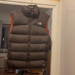 The North Face Nuptse väst - Säljer en vintage väst från The North Face. Västen har en pytteliten fläck på baksidan som syns på bilden. Säljer den för att den är lite för stor