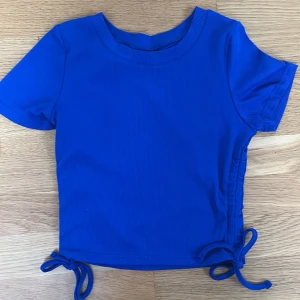 Blå t-shirt - Jättefin blå t-shirt med snören på sidorna. Använd ett fåtal gånger.  Jättebra skick