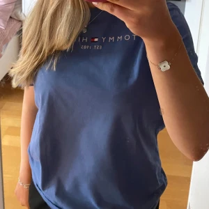 Blå Tommy Hilfiger t-shirt  - Unisex men använd av en tjej, storlek 176, sitter bra på mig som är s/m, använd men fortfarande i bra skick, är öppen för prisförslag.