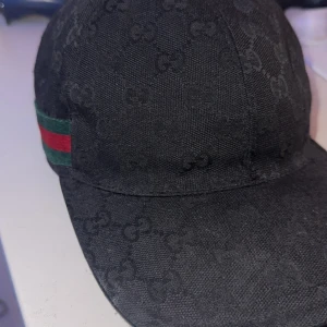Gucci keps  - Gucci keps storlek medium, köpt från Guccis hemsida förra sommaren.  Bra skick ända nackdel är där det är målat, jag skulle böja skärmen så släpptede lite så jag sydde ihop den lite men inget som syns när den sitter på, syns knappt upp o ner heller. 
