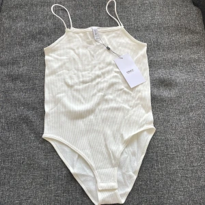 En ny oanvänd body med prislapp kvar på.  - Ny vit body S/M