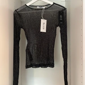 Glittrig mesh topp - En glittrig långärmad mesh topp. Aldrig använd med lappen kvar, är från NA-KD. 