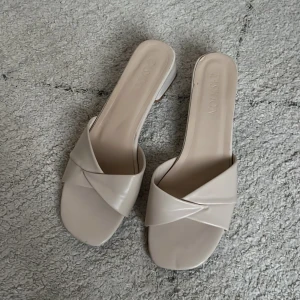 Beige sandaler med klack - Ett par eleganta beige sandaler med en liten klack. Sandalerna har en korsad remdesign över foten och en öppen tå. De är tillverkade i syntetmaterial och har en bekväm passform. Använd två kvällar!☺️🌟💛