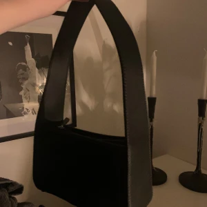 Svart liten väska - Svart liten väska med breda axelband. Stängs med dragkedja och är knappt använd. Köpt från zalando. 