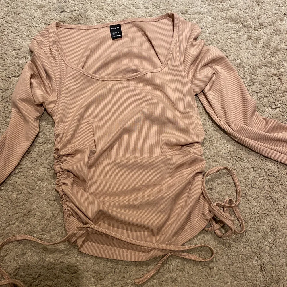 Supersöt långärmad tröja från SHEIN som är rufflad på sidan med snörning, skönt stretchigt material som sitter tajt mot kroppen. Använd 2-3 gånger men inte min stil längre🫶. Tröjor & Koftor.