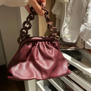 Vinröd mini handväska  - Super fin vinröd mini handväska. Väldigt unik i designen så den gör verkligen en outfit lite roligare. 