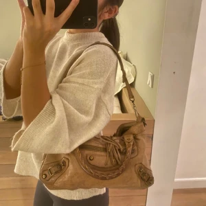 Balenciaga väska - Äkta Balenciaga City Leather handbag i brun färg. Lite sliten och någon fläck på utsidan därför säljs den för ganska billigt pris för en äkta. Äktbevis finns men har åkt av lädret den satt på, men kommer med i väskan. I väskan finns även en spegel💗💗