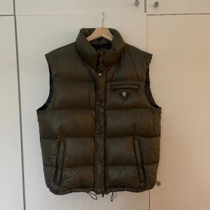 Prada väst - Mörkgrön Pradaväst Har tappat en del av knappen på loggan på bröstet (se bild 3) Mycket bra skick 