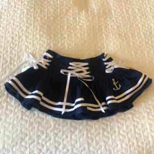 Minikjol - Köpt här på Plick! Kjolen är i använt skick, finns små defekter(bild 4,5). De två vita banden i kanten är ojämnt påsydda, det syns inte så tydligt men vill man kan jag skicka bild på det. Obs!! Väldigt kort!! Midjemått: 35 cm 