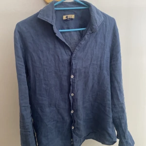 Blå linneskjorta  - Säljer nu min jätte snygga linne skjorta som köptes i Mallorca förra året. Skjortan köptes för 1800kr säljs nu endast för 250kr! Tröjan är perfekt nu inför sommaren då den är tunn och lätt.