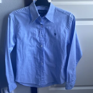 Ljusblå skjorta  - Snygg Ralph lauren skjorta i mycket fint skick. Storlek L i barnstorlek. Skulle säga att den passar S. Priset är inte hugget i sten och tveka inte på att fråga om du undrar något. 
