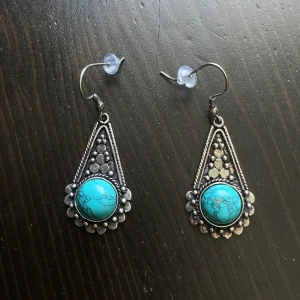 Silverfärgade örhängen med turkos sten, hängande, bohemisk, boho - Silverfärgade örhängen med turkos sten. Finns ett litet hack på ena kroken. Längd: 5 cm.