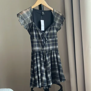 Klänning med inbyggda shorts - Rutig klänning från Urban Outfitters i storlek XS. Skön och luftig i materialet. Tajt i överdelen och lös i kjolen med inbyggda shorts som inte sitter tajt! Aldrig använd, lappen är kvar :)