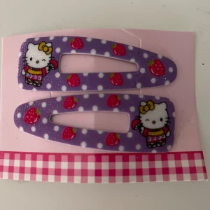 Nya 2 stycken Hello Kitty hårspännen,  lila med glitter  - Hello Kitty nya hårspännen som är jättefina och har lite glitter på sig. På den 3:e bilden Er ni storleken i relation till pennan som inte ingår. 