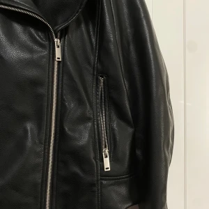 Skinnjacka - Svart skinnjacka i storlek (44). Jackan har två fickor på sidorna av jackan.  Andvänts 2-3 gånger.