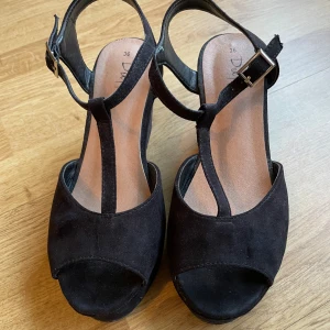 Svart sandal kilklack  - Snygg klacksandal i mocka. Använd fåtal gånger, inga skador. Strl 36