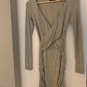 Grå klänning - Tajt klänning som sitter väldigt snyggt på! Har ett innerfoder som fått lite revor men inget som syns utanpå. 
