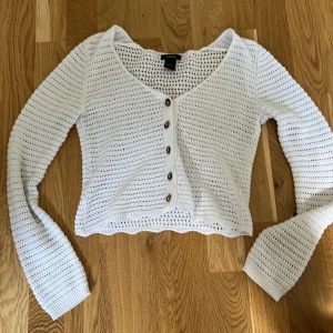 Vit stickad kofta från Lindex - Säljer en superfin vit stickad kofta från Lindex i storlek XS. Den har en v-ringad hals och knappar framtill. Koftan är croppad och har långa ärmar. 