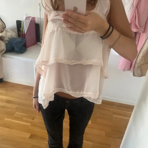 Vit ärmlös blus med spetsdetaljer - Säljer en söt vit ärmlös blus med spetsdetaljer. Blusen har en lös passform och är perfekt för sommaren. Den har två lager med spetskant som ger en fin och romantisk look. Perfekt för både vardag och fest!