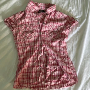 rutig topp  - Jättesöt rosa topp med knappar som gör att den går att styla på olika sätt! Sitter tyvärr lite för litet på mig, därav säljer jag den. Saknar defekter! ⭐️ Skriv vid fler frågor eller bilder💕