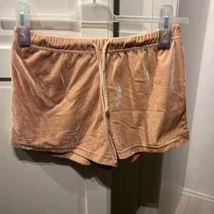 Beige shorts från BikBok - Ett par beige shorts från BikBok i storlek S. Shortsen har en elastisk midja och är tillverkade i ett glansigt material.