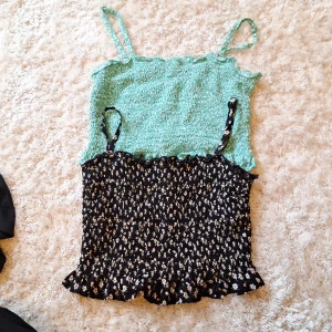 Två somriga linne-toppar - Säljer två supergulliga linne-toppar från Hollister i storlek XS. Den ena är mintgrön med volangdetaljer och den andra är svart med ett blommigt mönster. Båda topparna har smala axelband som går att spänna in. De är stretchiga och bekväma att ha på sig. De säljs även var för sig