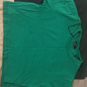 Grön t-shirt från Monki - Säljer en grön t-shirt från Monki i storlek XS. Den är i bomull och har en normal passform. Perfekt för vardagsbruk eller sommaraktiviteter. T-shirten är i bra skick och redo för en ny ägare!