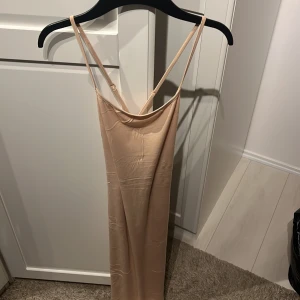 Beige klänning från Shein - En beige långklänning från Shein med smala axelband. Klänningen är tillverkad i ett lätt och mjukt material, vilket gör den bekväm att bära.