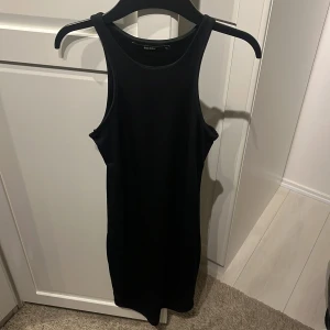 Svart klänning från BikBok - En svart ärmlös klänning från BikBok i storlek XS. Klänningen är tight och kort, perfekt för festliga tillfällen.
