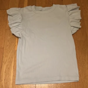 Babyblå volangtshirt  - Storlek 146/152. Ljusblå volang t-shirt från Gina tricot. Använd en gång, jättefint skick. 