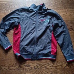 Svart och röd jacka från Quiksilver - Säljer en snygg svart och röd jacka från Quiksilver i storlek M. Jackan har en dragkedja framtill och en bröstficka med dragkedja. Den är gjord av polyester och har en normal passform. Perfekt för höst och vår!
