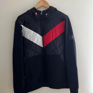 Svart jacka med huva och färgblock - Säljer en snygg marinblå Tommy Hilfiger cardigan/tunn jacka. Den är i nyskick, har använts 1 gång, passar inte längre (Storlek L)
