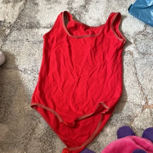 Linne body  -  En röd body som man kan ha under gymnastik träningar osv