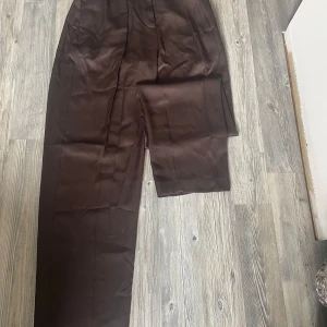 Kostymbyxor  - Ett par bruna kostymbyxor från primark i ett satin liknande material. Säljer då jag har rensat garderoben och kommer lägga upp en del annonser!